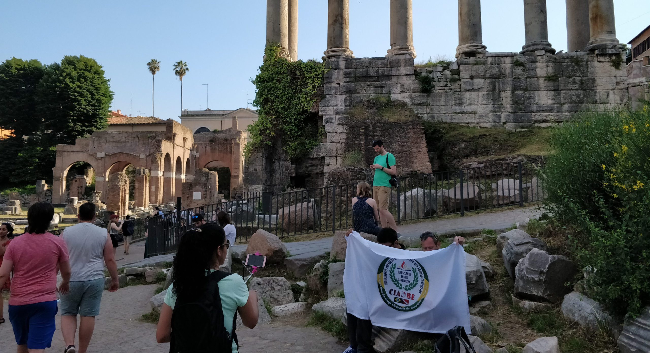 Tourists walking past the ruins of the Roman Forum on a sunny day